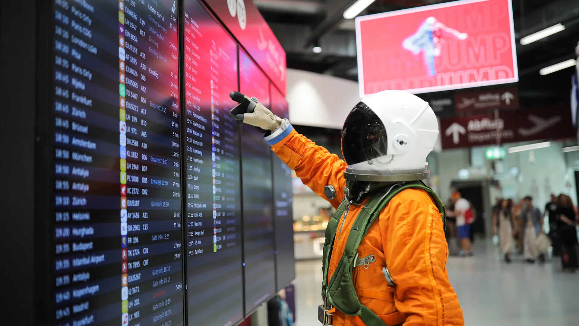 Ein Bild zeigt einen Astronauten in orangenem Anzug am Flughafen Berlin Brandenburg BER